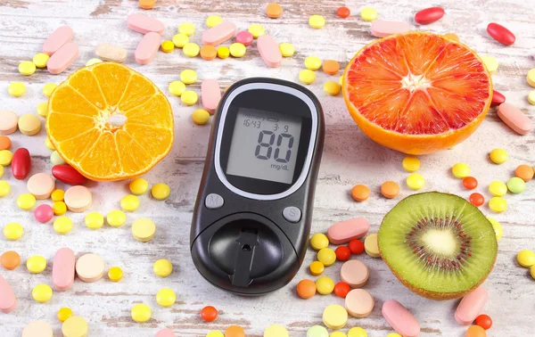 Glucometer with result, fruits and colorful medical pills, diabetes, healthy lifestyle and nutrition