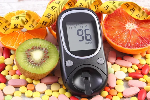 Glucose meter with result, centimeter, fruits and medical pills, diabetes, slimming, healthy lifestyle and nutrition