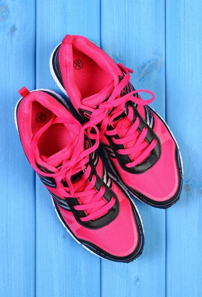 Pair of pink sport shoes on blue boards background