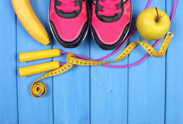 Pair of sport shoes, fresh fruits and accessories for fitness on blue boards, copy space for text
