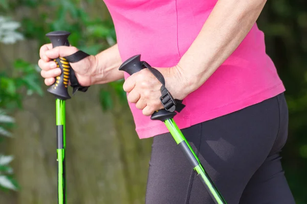 Hand of elderly senior woman with nordic walking sticks, sporty lifestyles in old age