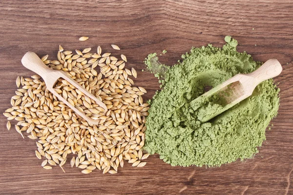 Heap of young powder barley and barley grain on wooden background, body detox