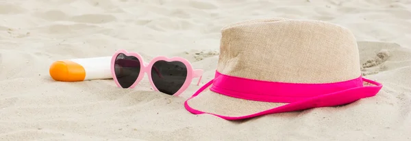 Sunglasses, straw hat and sun lotion on sand at beach, sun protection, summer time