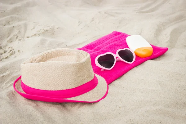 Sunglasses, straw hat and sun lotion on sand at beach, sun protection, summer time