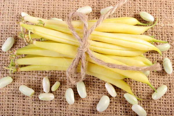 Seeds and stack of yellow beans on jute canvas, healthy food