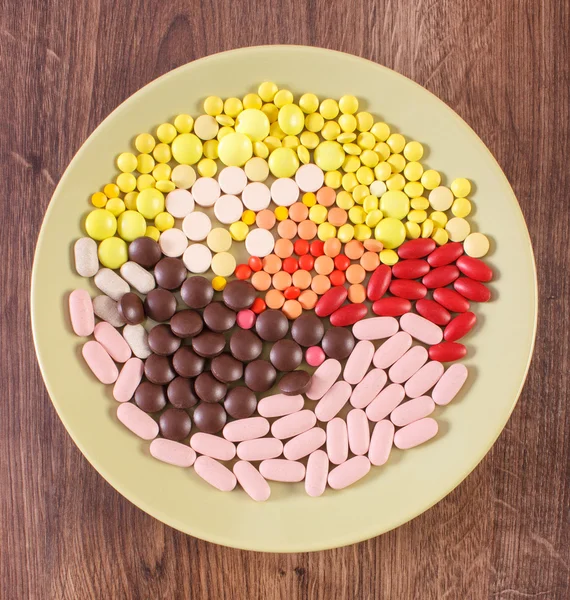 Colorful medical pills, tablets and capsules on plate, health care concept