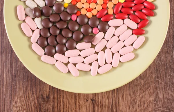 Colorful medical pills, tablets and capsules on plate, health care concept