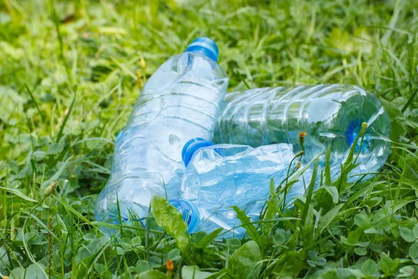 Plastic bottles of mineral water on grass in park, littering of environment