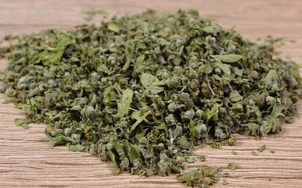 Heap of dried green marjoram on wooden background