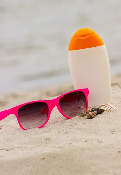 Seasonal concept, shells, pink sunglasses and sun lotion