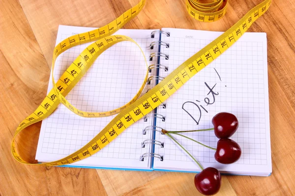 Cherry and centimeter with notebook, slimming and healthy food