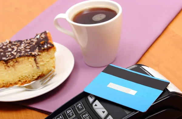 Paying with contactless credit card for cheesecake and coffee in the cafe, finance concept