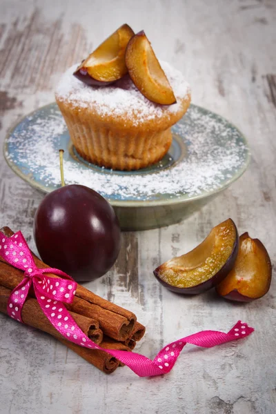 Fresh baked muffins with plums and powdered sugar on plate, delicious dessert