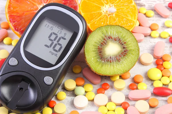 Glucometer with result, fruits and medical pills, diabetes, healthy lifestyle and nutrition