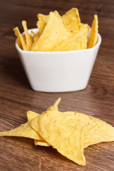 Salted potato crisps in bowl on board, concept of unhealthy food