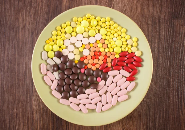 Colorful medical pills, tablets and capsules on plate, health care concept