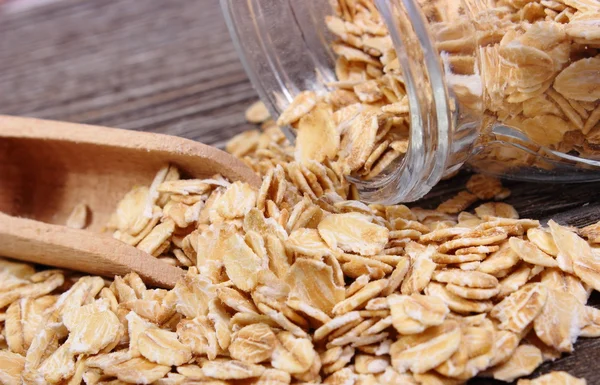 Oat flakes spilling out of jar on wooden background