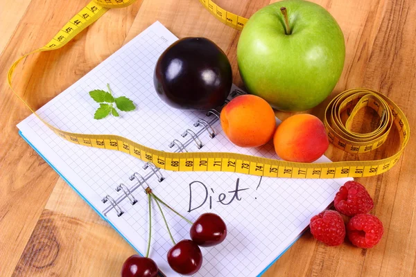 Fruits and centimeter with notebook, slimming and healthy food