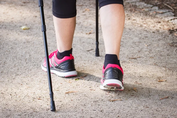 Legs of elderly senior woman practicing nordic walking, sporty lifestyles in old age