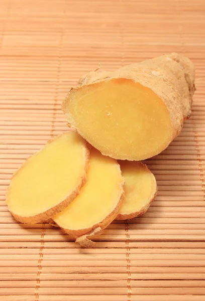 Slice and root of ginger on wooden background