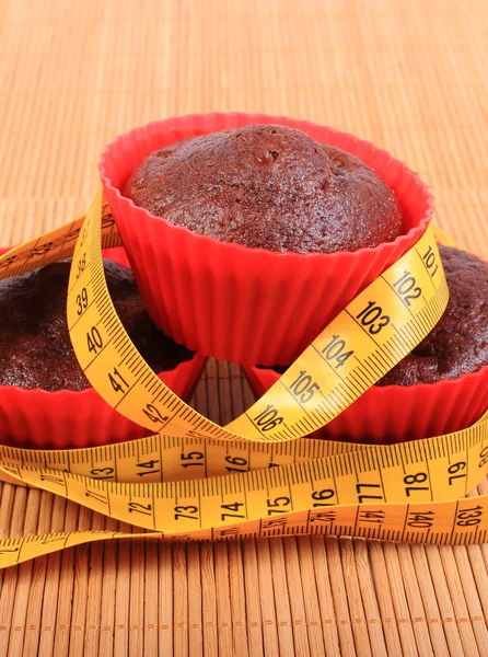 Chocolate muffins in red cups and tape measure