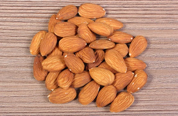 Heap of almonds on wooden background