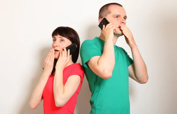 Shocked woman and man talking on mobile phone