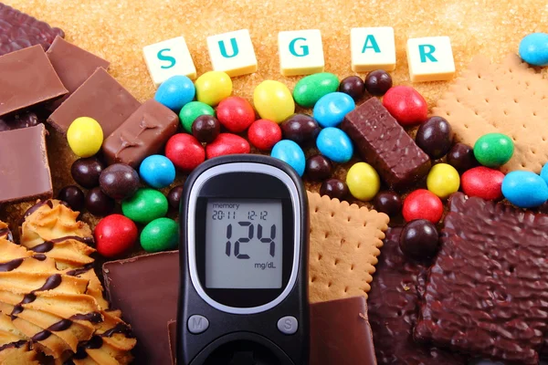 Glucometer, sweets and cane brown sugar with word sugar, unhealthy food