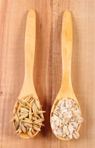 Organic oat grains and oatmeal on wooden spoon, healthy nutrition