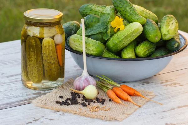 Cucumbers in metal bowl, vegetables and spices for pickling and jar pickled cucumbers