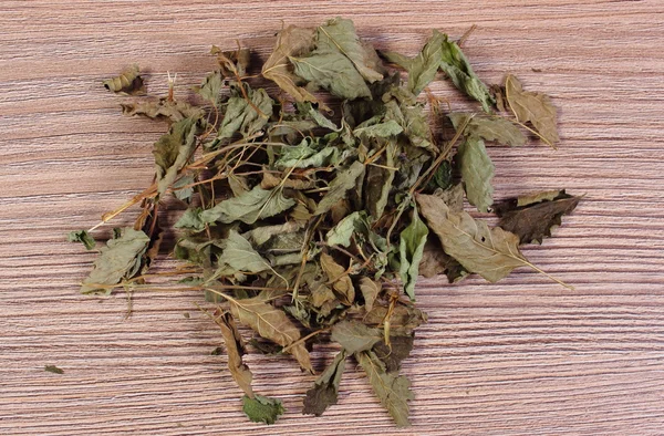 Heap of dried lemon balm on wooden surface