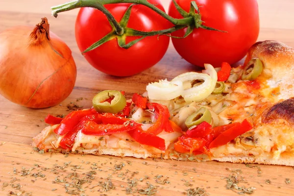 Vegetarian pizza, tomatoes onion and seasoning on wooden surface