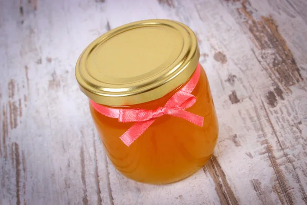 Fresh organic honey in glass jar on wooden background, healthy nutrition and strengthening immunity