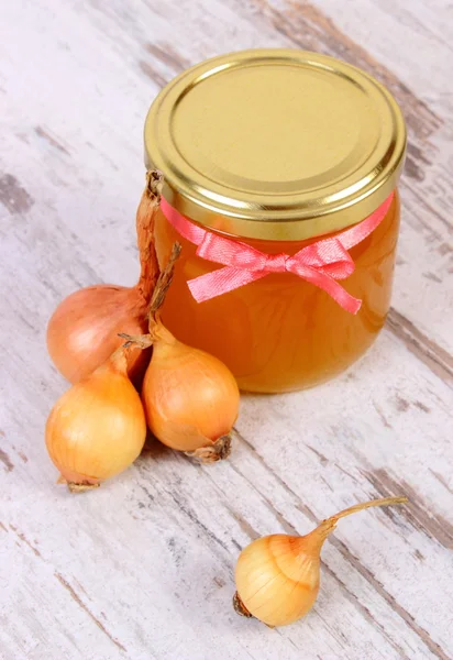 Fresh organic honey in glass jar and onions on wooden background, healthy nutrition and strengthening immunity