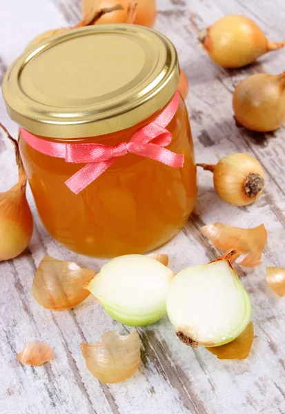 Fresh organic honey in glass jar and onions on wooden background, healthy nutrition and strengthening immunity