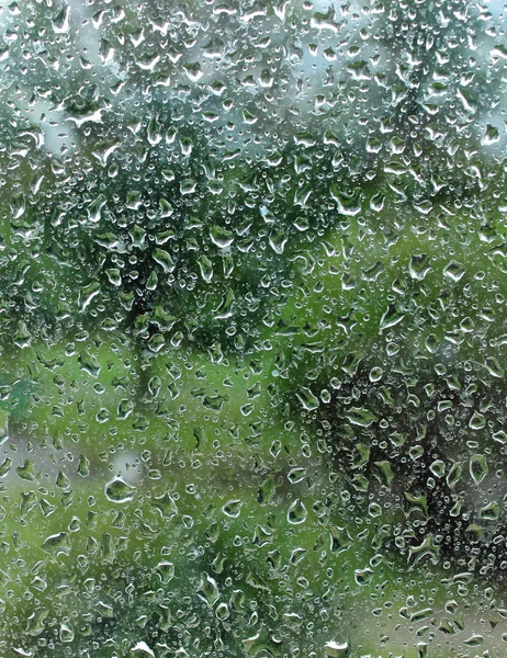Dripping down drops of rain on glass