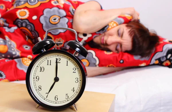 Brunette woman sleeping in her bedroom, ringing alarm clock