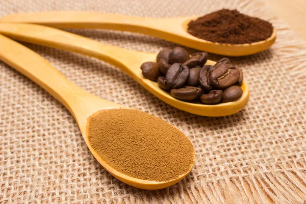 Grains, ground and instant coffee with wooden spoon on jute canvas