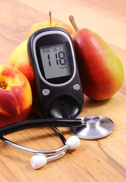 Glucose meter with medical stethoscope and fresh fruits