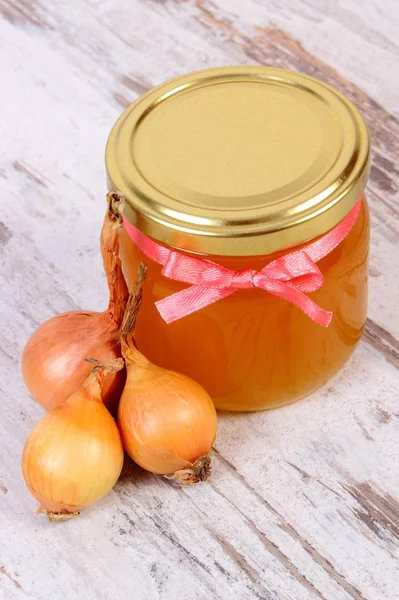 Fresh organic honey in glass jar and onions on wooden background, healthy nutrition and strengthening immunity