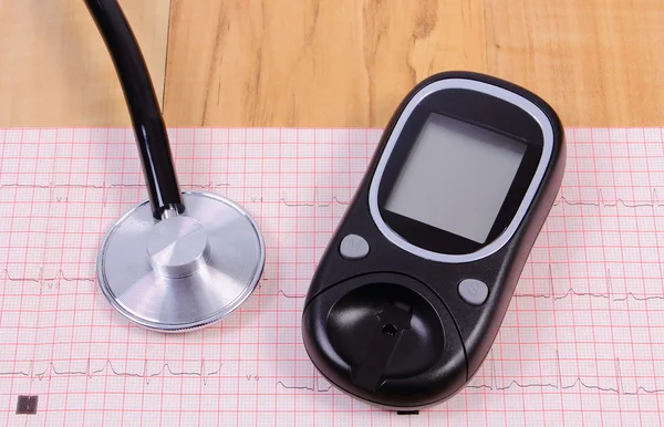 Glucometer and stethoscope on electrocardiogram graph