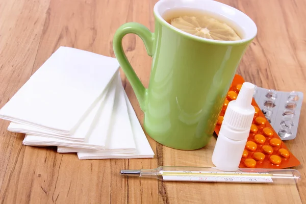 Pills and nose drops for colds, handkerchiefs and hot tea with lemon