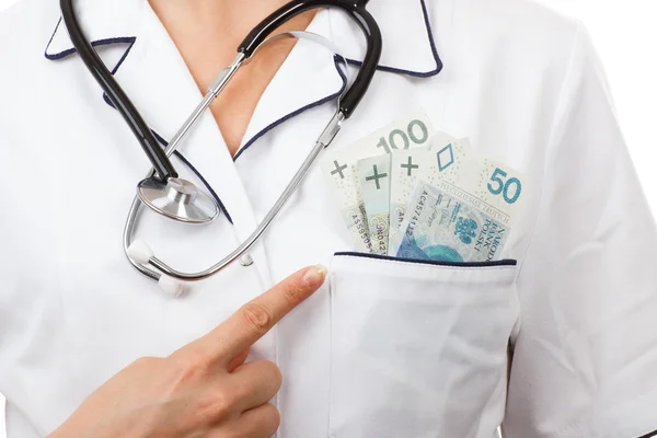 Woman doctor with stethoscope showing polish currency money in apron pocket, corruption or bribe concept