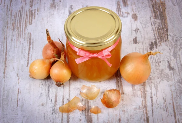 Fresh organic honey in glass jar and onions on wooden background, healthy nutrition and strengthening immunity