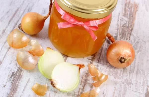 Fresh organic honey in glass jar and onions on wooden background, healthy nutrition and strengthening immunity