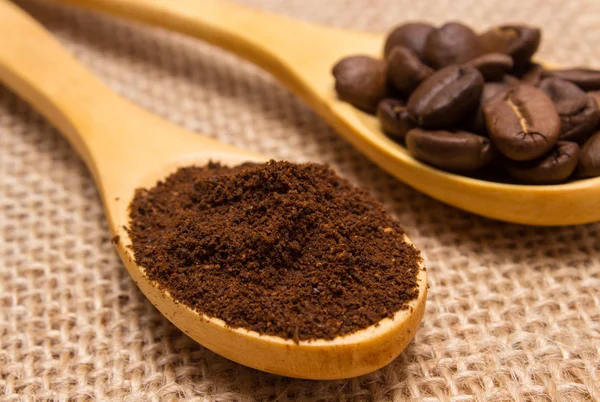 Ground coffee and grains with wooden spoon on jute canvas