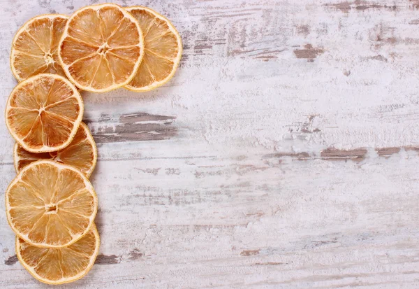 Slices of dried lemon on old wooden background, copy space for text