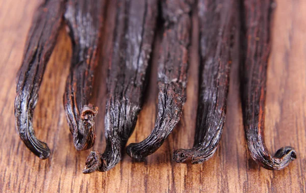 Fragrant vanilla sticks on wooden surface plank