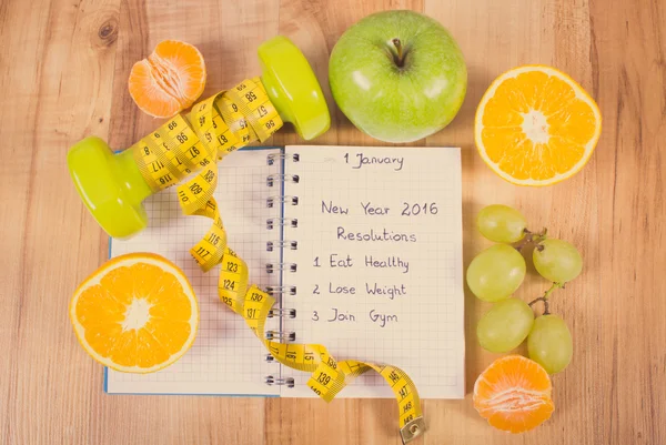 Vintage photo, New years resolutions written in notebook and dumbbells with centimeter