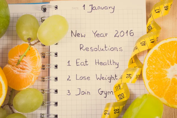 Vintage photo, New years resolutions written in notebook and fruits, dumbbells with centimeter